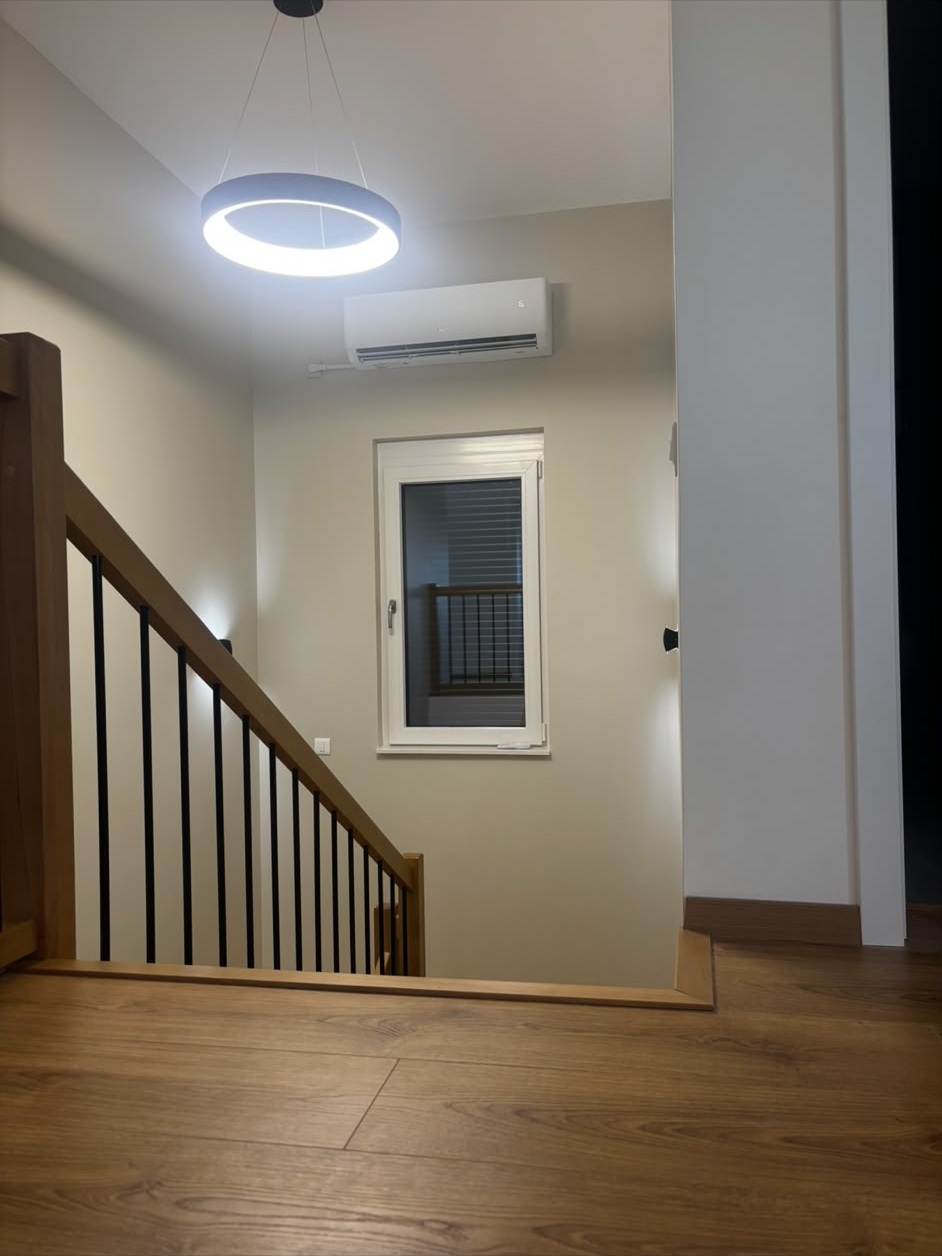 Cage d’escalier d’une maison repeinte en gris très clair avec garde-corps en bois