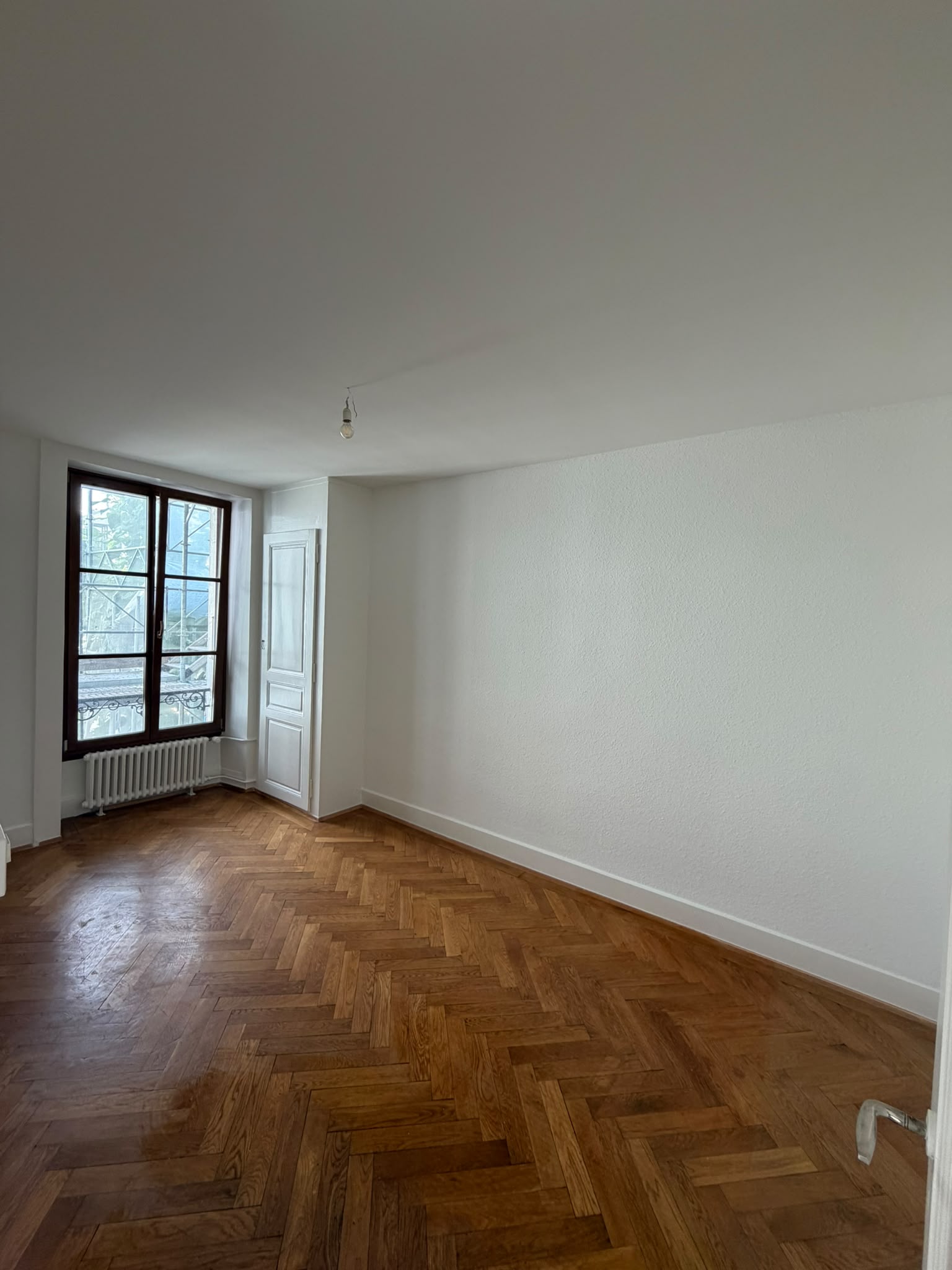 Chambre aux murs et plafond repeints en blanc, porte et encadrements laqués, parquet à bâtons rompus
