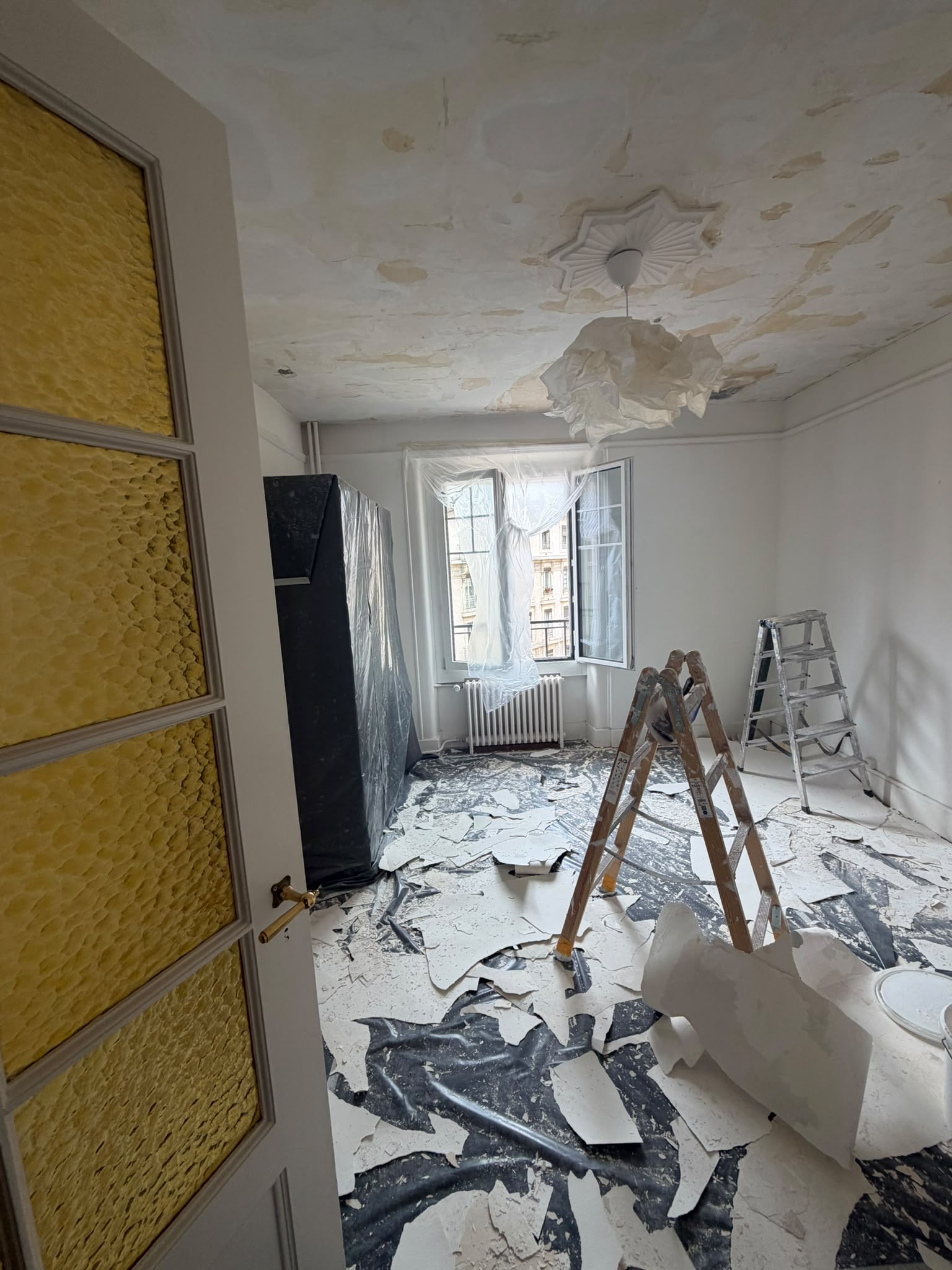 Avant : plafond écaillé et peinture décollée dans une chambre d’appartement ancien, escabeaux et bâches en place