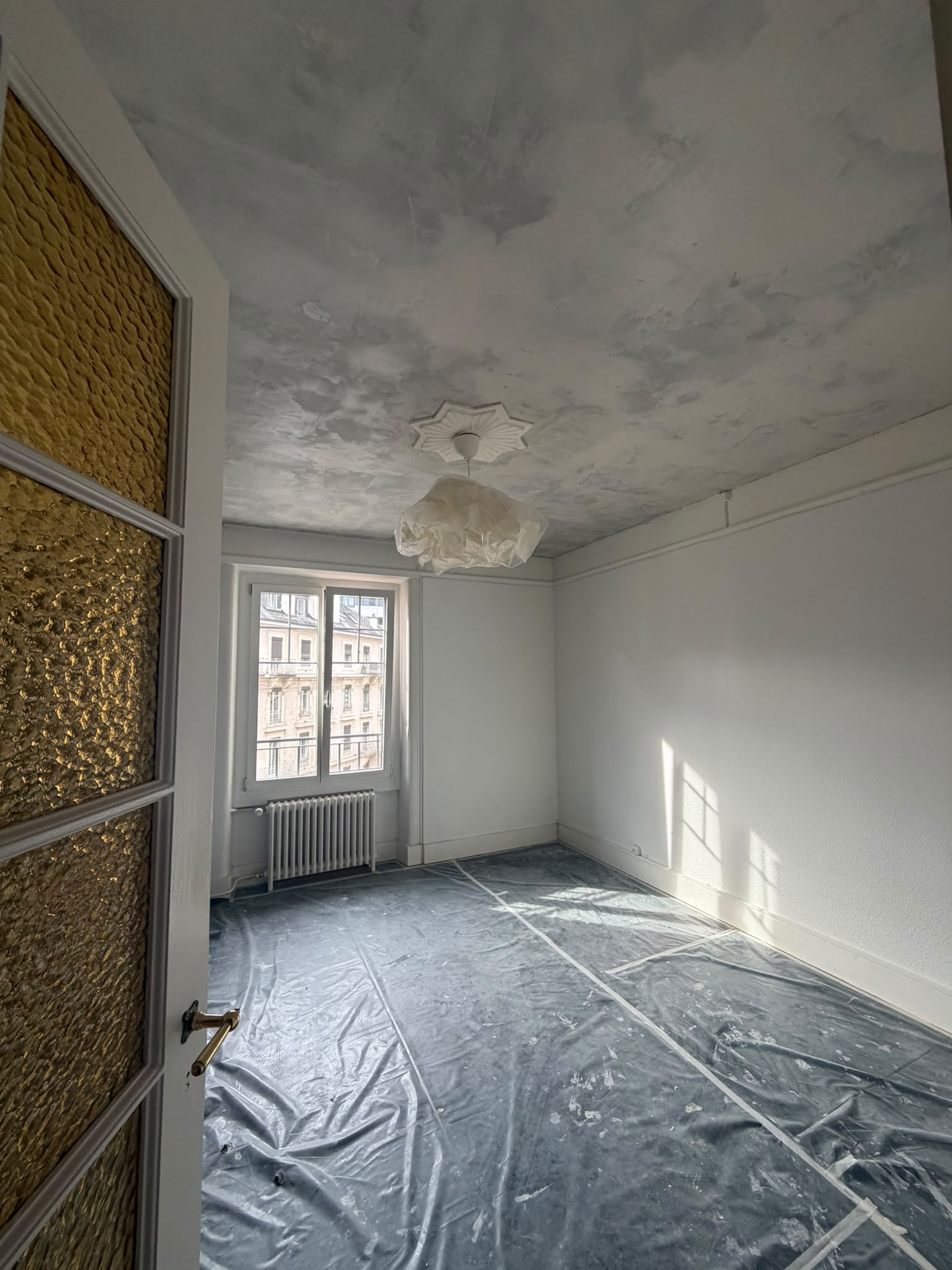 Pendant : plafond entièrement enduit et poncé avant peinture, rosace conservée, sol bâché