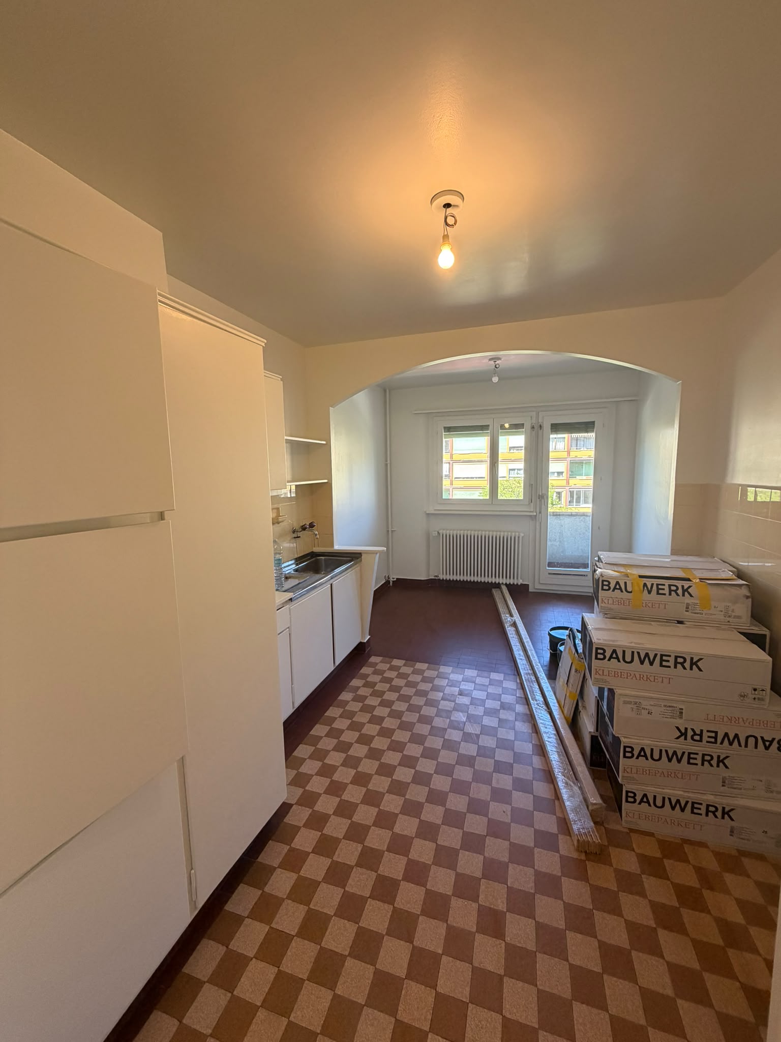 Cuisine en cours de rénovation : boiseries et plafond repeints en blanc, cartons de parquet avant pose