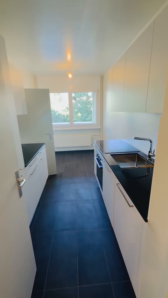 Cuisine aux murs et plafond peints en blanc, meubles blancs et sol anthracite